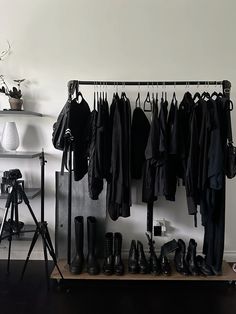 a bunch of clothes hanging on a rack in a room with a camera and tripod