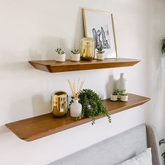 two wooden shelves on the wall above a bed in a room with white walls and pillows