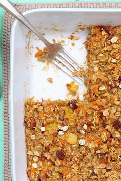 a square white dish filled with granola and carrots next to a fork in it