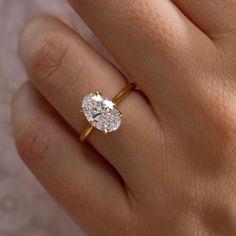 a woman's hand with a diamond ring on top of her finger and an engagement band