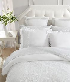 a bed with white sheets and pillows in a room