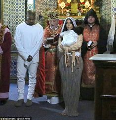 some people are standing in front of a priest and another person is holding a baby