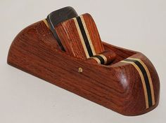 a cell phone holder made out of wood with stripes on the sides and a pocket in the middle