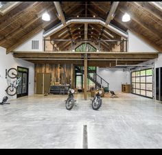 two motorcycles are parked in the middle of a large room with high ceilings and wooden beams