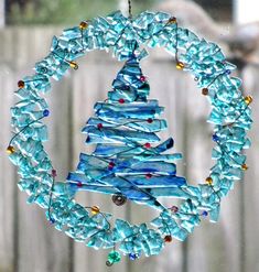 a blue glass christmas tree ornament hanging from a chain on a wooden fence