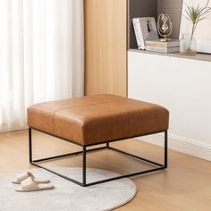 a brown footstool sitting on top of a wooden floor next to a window