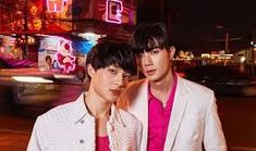 two young men standing next to each other in front of a city street at night