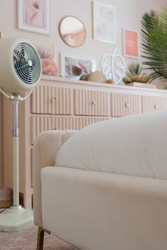 a white couch sitting next to a table with a fan on it's side