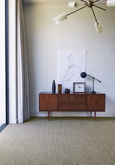 a living room area with a table, lamp and pictures on the wall above it