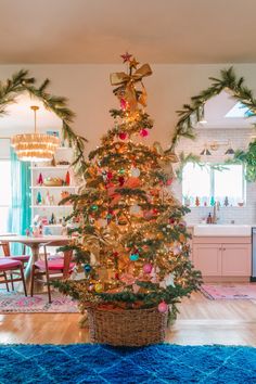 a decorated christmas tree in the middle of a living room with blue carpet and pink chairs