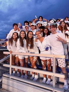 a group of people standing on top of a bleachers next to each other