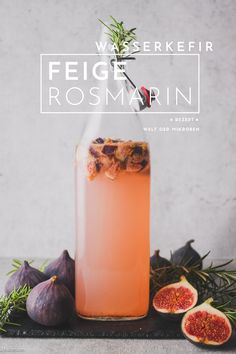 a bottle filled with liquid next to figs and rosemary