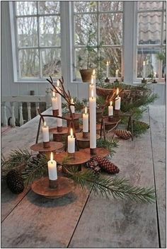 a wooden table topped with lots of candles and pine cones on top of each other