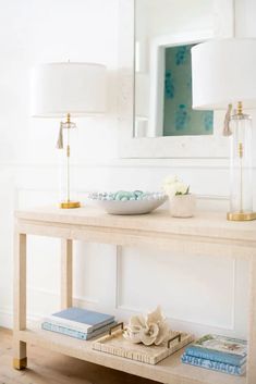 a table with a bowl on top of it next to a mirror and lamp in a room