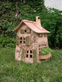 a small clay house sitting in the grass