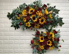 two sunflowers and other flowers hanging on a brick wall