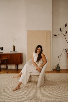 a woman sitting in a chair with her legs crossed on the floor next to a wall