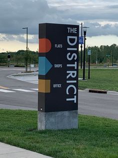 a large sign sitting on the side of a road next to a grass covered field