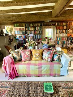 a living room filled with lots of furniture and bookshelves full of books on top of them