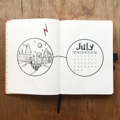 an open notebook with the word july written on it and a drawing of a city