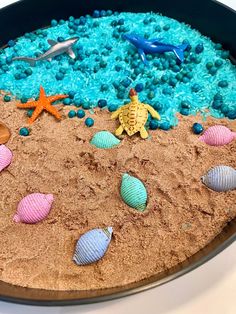 a sand tray filled with sea shells and other marine life on top of a white table