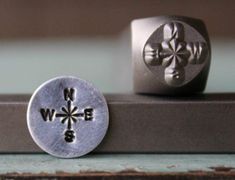 two metal buttons sitting next to each other on top of a piece of wood,