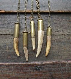 four necklaces with different types of horns hanging from chains on a wooden surface,