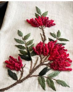 a close up of a piece of cloth with flowers and leaves embroidered on the fabric