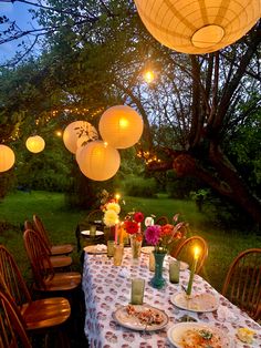 an outdoor dining table with paper lanterns hanging from the ceiling