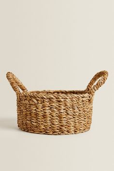 a woven basket with two handles on the bottom and one handle at the top, against a white background