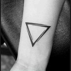 a black and white photo of a small triangle tattoo on the left inner arm,