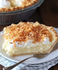 a slice of coconut cream pie on a white plate with a silver fork next to it