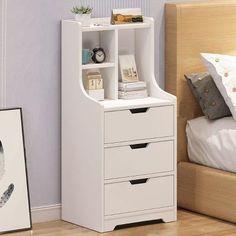 a white bookcase with drawers in a bedroom next to a bed and framed pictures