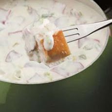 a spoon with some food in it on top of a pot filled with milk and sour cream