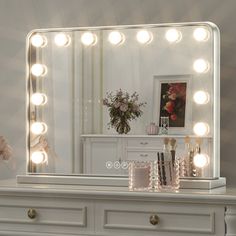 a white dresser topped with a large mirror and lots of lights on top of it