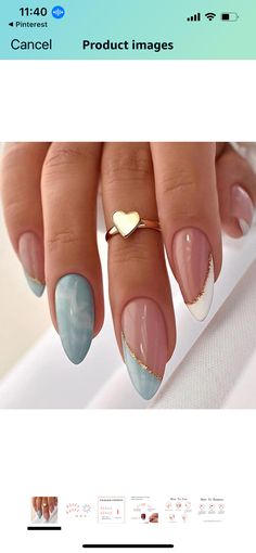 a woman's hand with blue and white nail polish on it, holding a gold heart ring