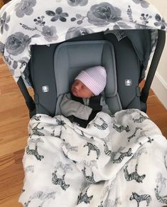 a baby sleeping in a car seat with a blanket on it's back and head