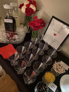 there are many wine glasses on the table with flowers in vases and cards next to them