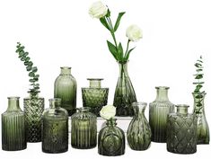 a group of green vases and flowers on a table