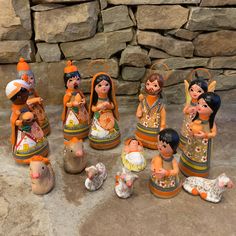 a group of ceramic figurines sitting on top of a stone floor next to a pile of rocks