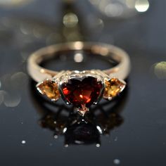 A Ladies 14K Yellow Gold Ring Set With A 6X6 Mm Heart Cut Red Garnet And 2 - 4X4 Mm Heart Cut Orange Garnets. The Ring Is Size 9 Heart Cut Multi-stone Anniversary Rings, Luxury Red Heart Cut Jewelry, Luxury Red Heart-cut Jewelry, Red Heart-shaped Rings With Center Stone, Heirloom Heart-shaped Gemstone Ring, Fine Jewelry Heart Cut Multi-stone Rings, Red Heart Shaped Rings With Accent Stones, Red Heart-shaped Rings With Accent Stones, Red Heart-shaped Hallmarked Jewelry