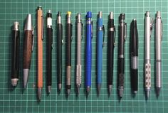 several different types of pens lined up next to each other on a green table top