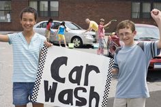 two boys holding up a car wash sign