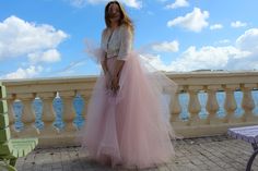 a woman in a pink tulle skirt standing on a balcony next to a bench