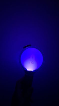 a person holding up a blue light in the dark with their hand on top of it