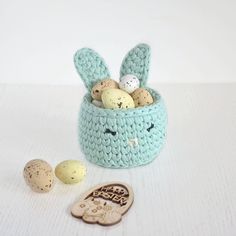 a crocheted basket filled with eggs next to a rubber stamp