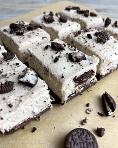 oreo cookie bars with white frosting and chocolate chips are on a piece of parchment paper