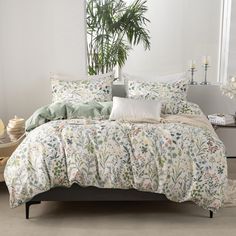 a bed with white and green comforters in front of a mirror