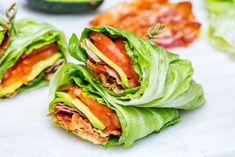 two lettuce wraps with bacon and avocado on the side, cut in half