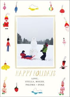 two children playing in front of a snowman with other holiday ornaments around it and the words happy holidays above them